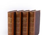 three old books sitting on top of each other on a white surface
