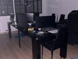 un bureau noir sur lequel se trouve un ordinateur, dans une pièce