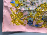 an image of a pink and gold scarf with a coat of arms on it