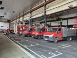several red trucks are parked in a garage with a man on a lift