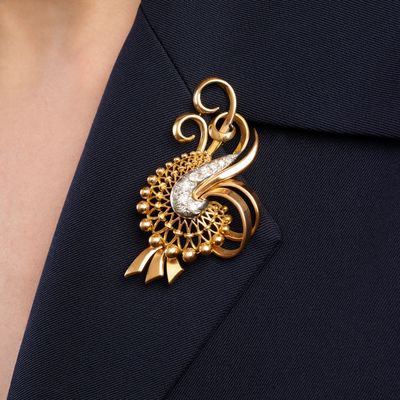 gold tone broochle with a white and clear crystal in the center
