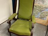a green chair sitting in a room with a map on the wall