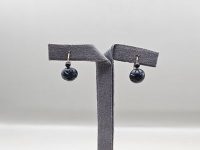 une paire de boucles d'oreilles avec des perles noires sur un support