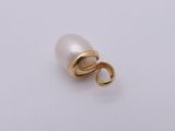 a close up of a pearl and gold charm on a white surface