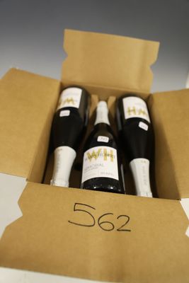 trois bouteilles de vin dans un carton sur une table