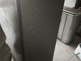 a black refrigerator sitting in a room with a person standing next to it