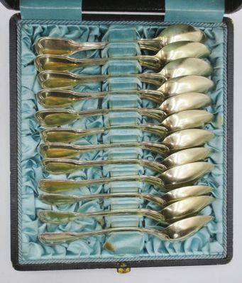 six cuillères en argent dans un étui bleu posé sur une table