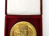 an image of a gold medal in a red box on a white surface