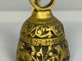 une vieille cloche en laiton entourée d'une corde, posée sur une surface blanche