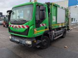 un camion-poubelle vert garé sur un parking