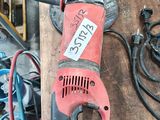 a red and black electric drill on a wooden table