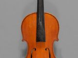 un vieux violon posé sur une table près d'un mur gris