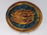 une assiette en céramique ornée d'un oiseau, posée sur un socle