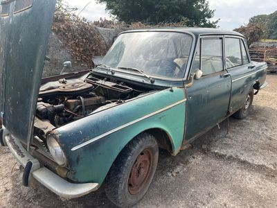 une vieille voiture dont le capot est cassé, garée dans la poussière