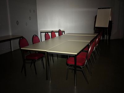 des tables et des chaises dans une pièce où est accroché un tableau blanc au mur