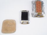 two pieces of metal and a piece of plastic on a white surface