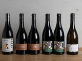 six bouteilles de vin sont alignées sur une table en bois