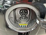 a close up of a car ' s charging station with a car in the background