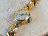 a gold wrist watch sitting on a piece of wood