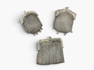 trois sacs à main en maille métallique argentée posés sur une surface blanche