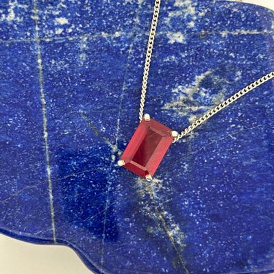 sterling silver necklace with a red square stone on a blue stone slab