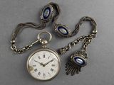 an image of a silver pocket watch with a chain and evil eye charms