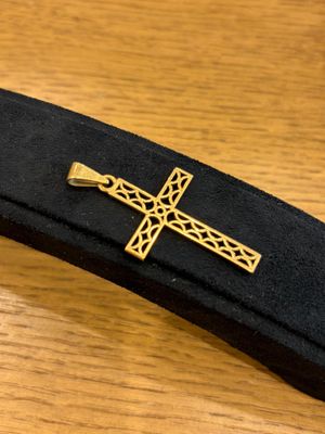 black and gold tie bar with a cross on it on a wooden table