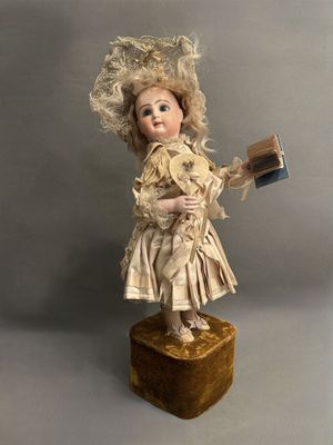 an old fashioned doll with a book and hat on top of a wooden block