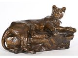 une statue en bronze représentant un lion couché sur un rocher