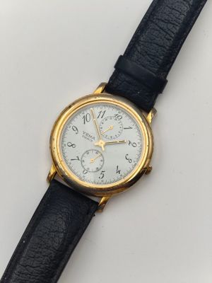 gros plan d'une montre sur une surface blanche avec un bracelet noir