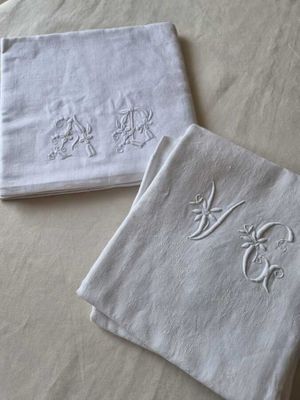 deux serviettes blanches ornées de monogrammes brodés, posées sur un lit