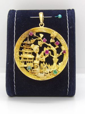 une image représentant un pendentif plaqué or sur lequel figurent un homme et une femme dans un paysage
