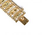 a close up of a gold bracelet on a white surface
