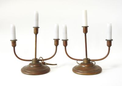 une paire de chandeliers anciens en laiton avec des bougies blanches