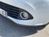 the front end of a white car with a number plate on it