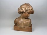 statue d'un jeune garçon aux cheveux bouclés, assis sur un bloc de bois