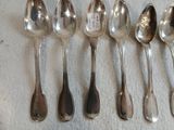 six cuillères en argent sont alignées sur une table
