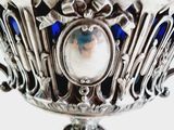 a silver bowl with a blue glass in it