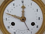 a gold clock with roman numerals on the face