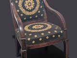 une chaise ancienne en bois dont l'assise est recouverte d'un tissu à motifs noirs et dorés
