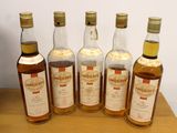 six bottles of whisky sitting on top of a wooden table