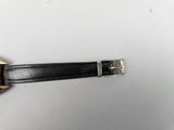an image of a black watch with a gold buckle on a white surface