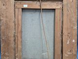 an old picture frame hanging on a wooden easel against a blue wall