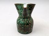 a green vase that is sitting on a white surface