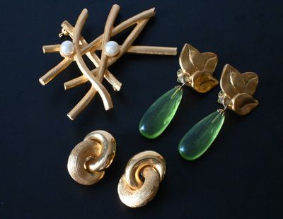 gold and green earrings and brooches on a black surface