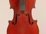 un vieux violon rouge posé sur une surface blanche
