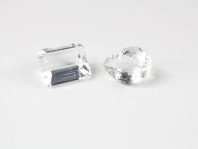 une paire de pierres de quartz transparent facettées posées sur une surface blanche