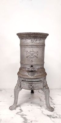 a small metal pot sitting on a stand on a marble floor