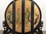 une image représentant un paravent oriental noir et doré orné de fleurs et d'arbres