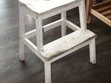 a white wooden step stool sitting on a hard wood floor